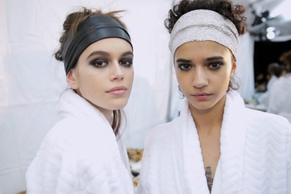 Kaia Gerber backstage with models at Tom Ford Beauty FW18 during New York Fashion Week, showcasing the bold "Extreme" collection look.