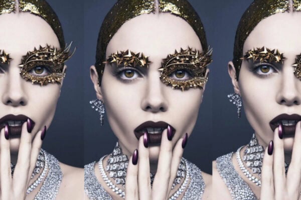Pat McGrath Labs Brand Essentials Film - Model wearing gold sculptural eye makeup, dark lipstick, jeweled nails, and diamond jewelry, showcasing Pat McGrath’s visionary beauty style.